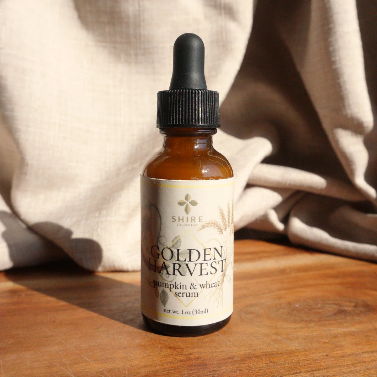 Bottle of Golden Harvest serum with a dropper on a wooden surface