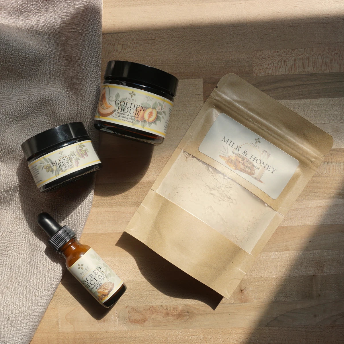 Skincare products including jars, a dropper bottle, and a pouch on a wooden surface.