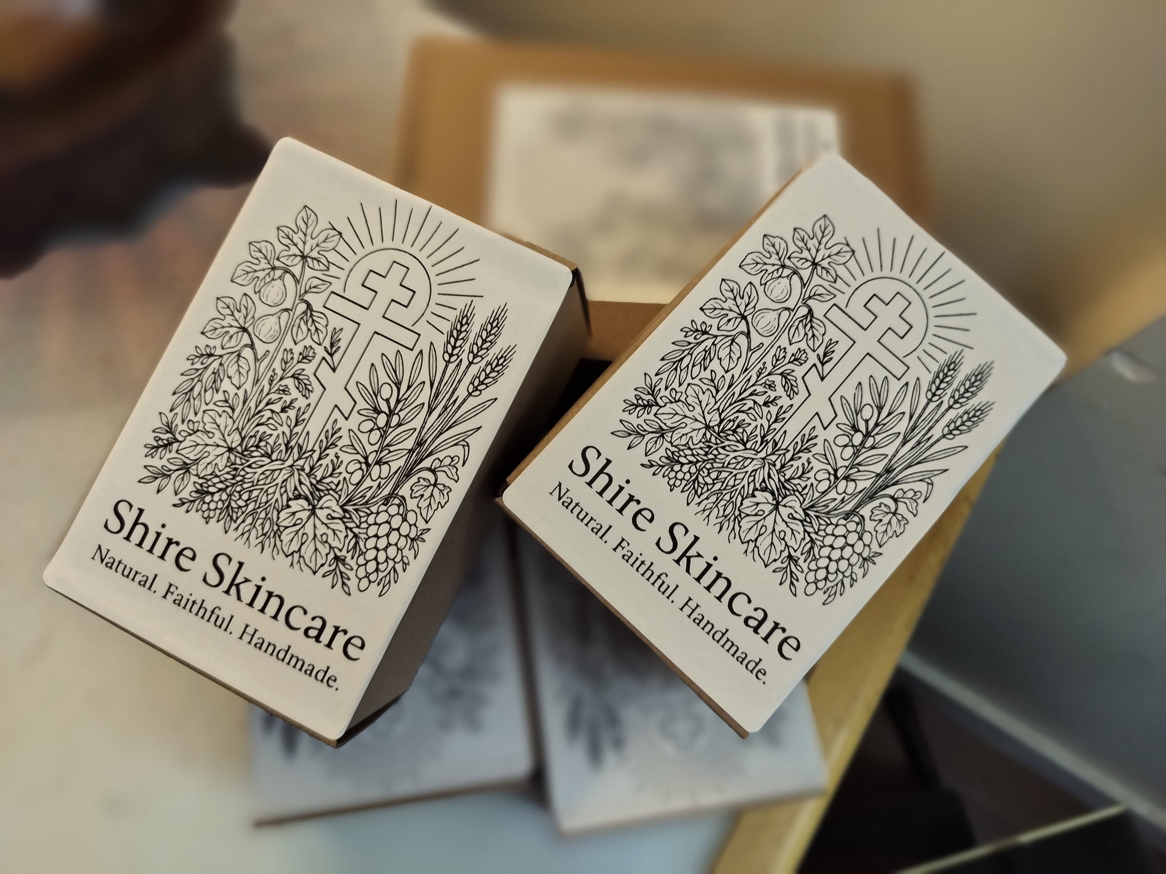 Shire Skincare product packaging with three bar cross design on a blurred background