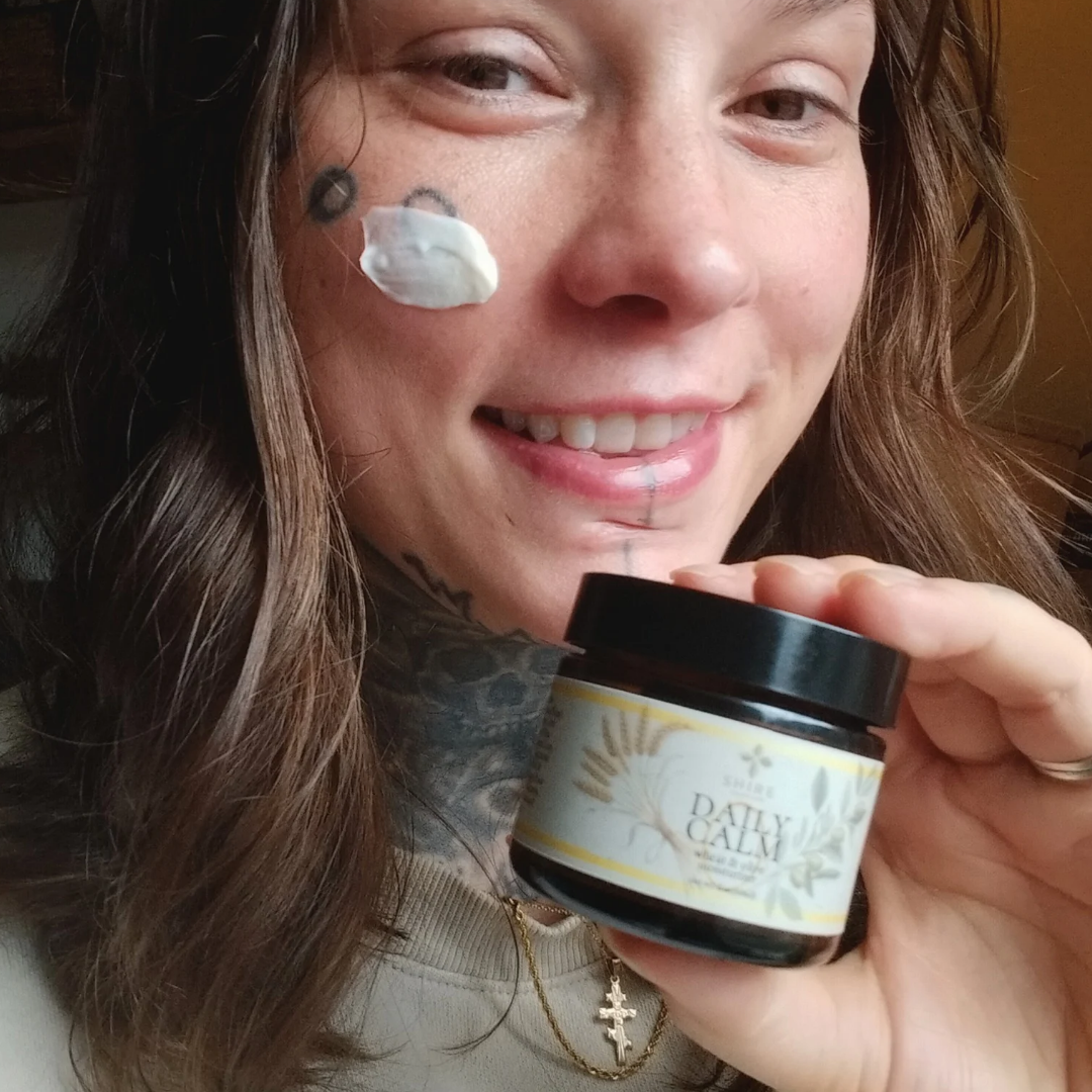 Person holding a jar of biblical skincare called 'Daily Calm' moisturizer with a neutral background