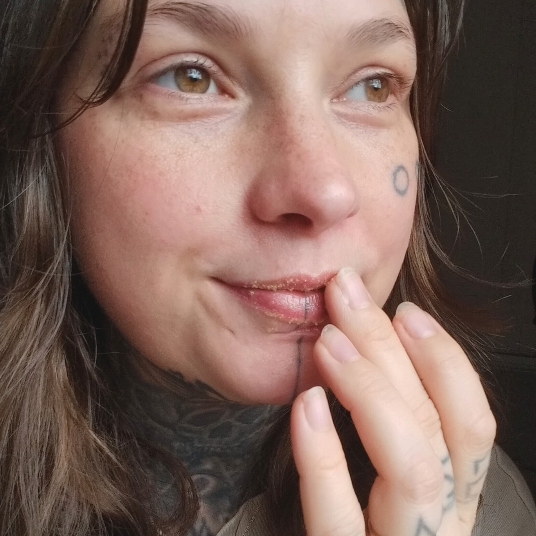 Close-up of a person using a lip scrub called "Sweet Words" on their lips.